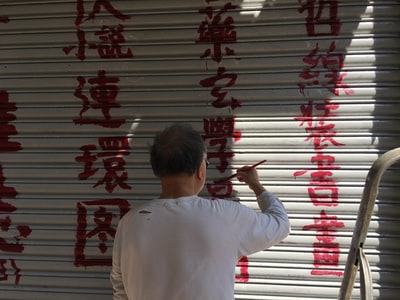 男子在卷帘门上画汉字文字